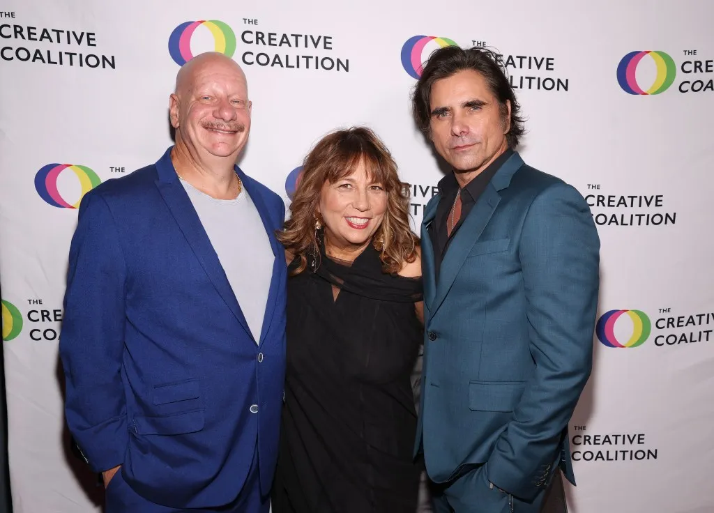 جون ستاموس مع اثنين من الحضور في حفل جوائز The Creative Coalition السنوي، يعكس دعمهم للعمل الإنساني والدفاع عن حقوق الأطفال.