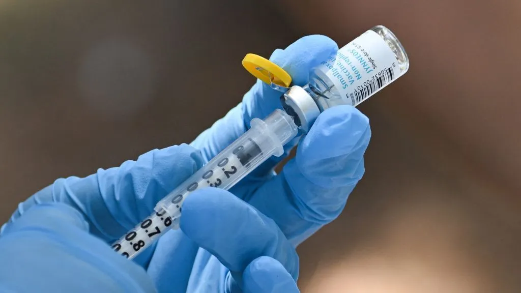 يد يرتدي قفازاً طبيًا يحضر حقنة من لقاح ضد فيروس الجدري القردي Mpox للوقاية من العدوى.