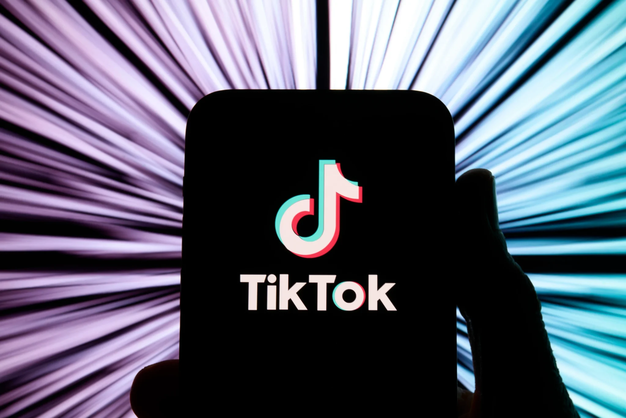 شعار تطبيق TikTok على شاشة هاتف ذكي مع خلفية ألوان متدرجة، يرمز لإطلاق ميزات التسوق بالذكاء الاصطناعي والدفع بنقرة واحدة داخل التطبيق.