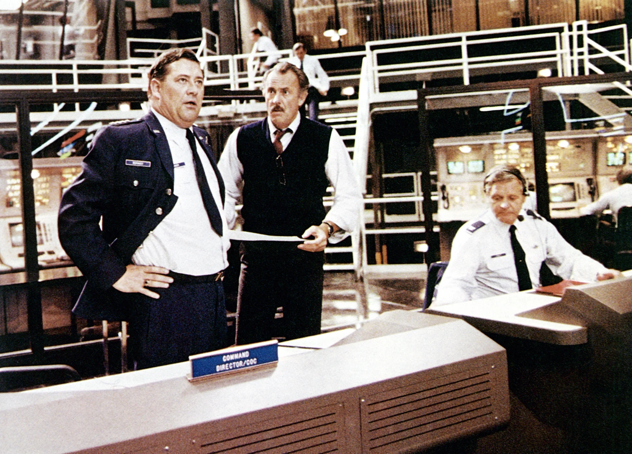 مشهد من فيلم "WarGames" يظهر ضباطاً عسكريين في مركز قيادة دفاع جوي أمريكي يناقشون تهديدات الحرب النووية في سياق سرد الفيلم الذي يعكس مخاوف الذكاء الاصطناعي والحرب الباردة.