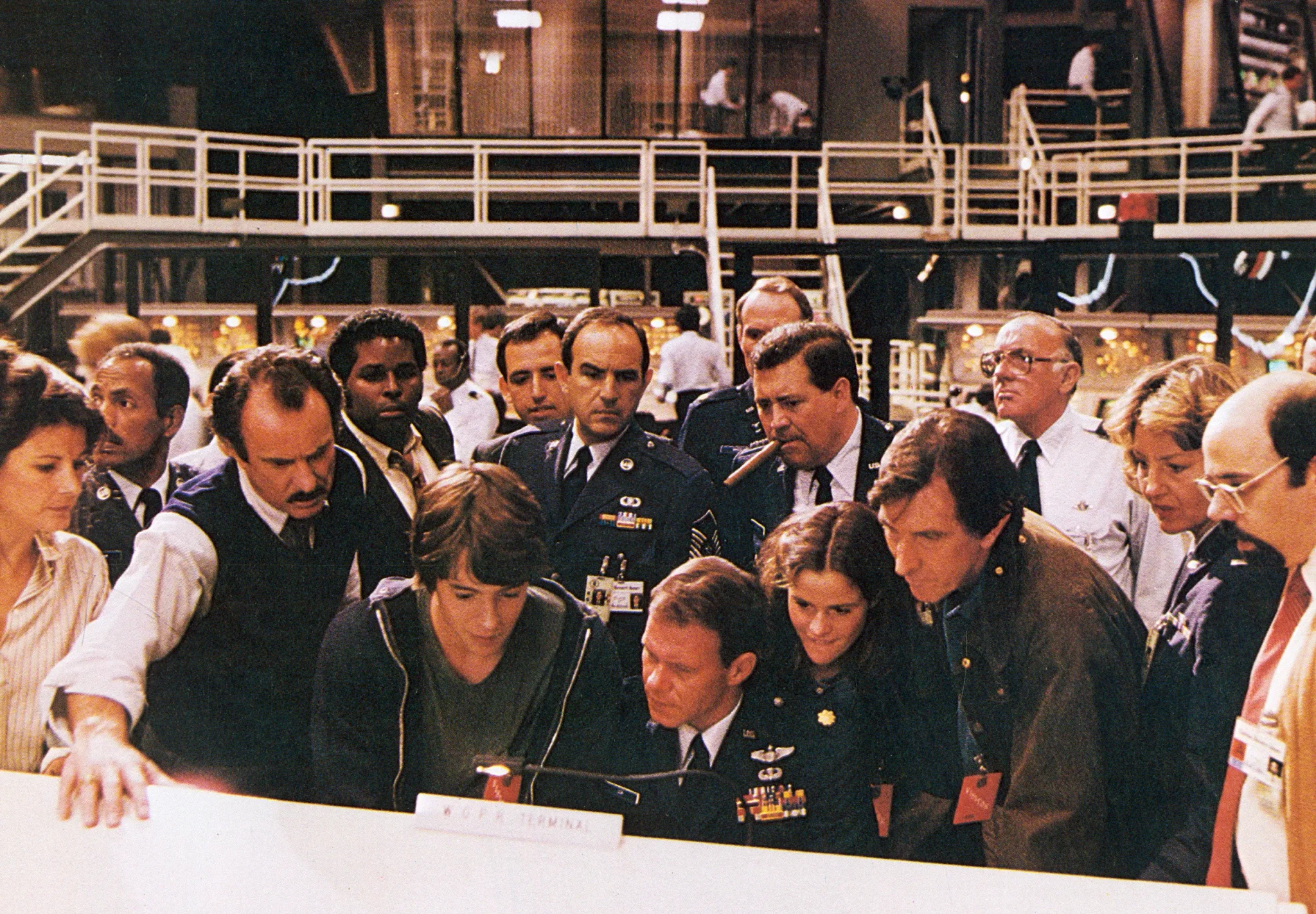مجموعة من العسكريين والعاملين يراقبون شاشة حاسوب في مشهد من فيلم WarGames الذي يعكس مخاوف الحرب الباردة والذكاء الاصطناعي.