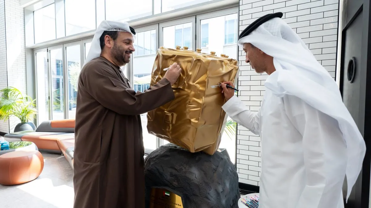 رجلان إماراتيان يوقعان على نموذج نصف حجم لمركبة هابطة ضمن مهمة الإمارات لاستكشاف حزام الكويكبات لعام 2028.
