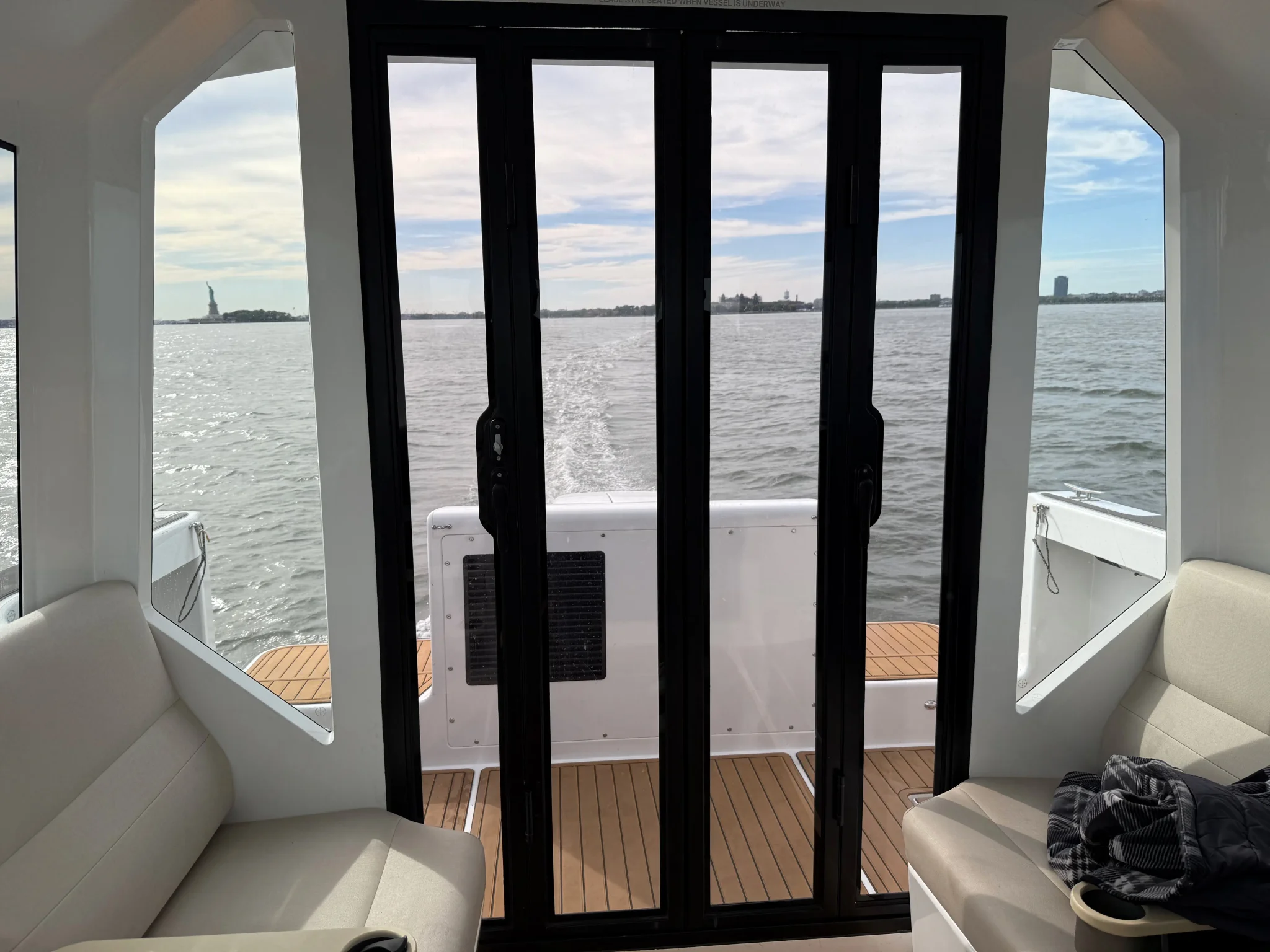 منظر من داخل العبارة الكهربائية VS-9 يظهر نهر East River في نيويورك مع تمثال الحرية في الخلفية، يعكس تجربة النقل الحضري بتقنية الهيدروفويل.